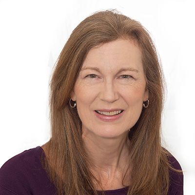 Professional headshot of a smiling woman with long brown hair wearing a purple top